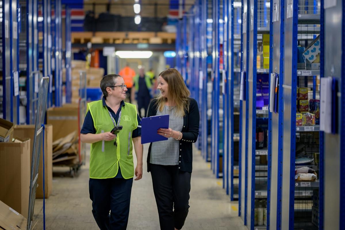 Warehouse staff walking through a distribution aisle