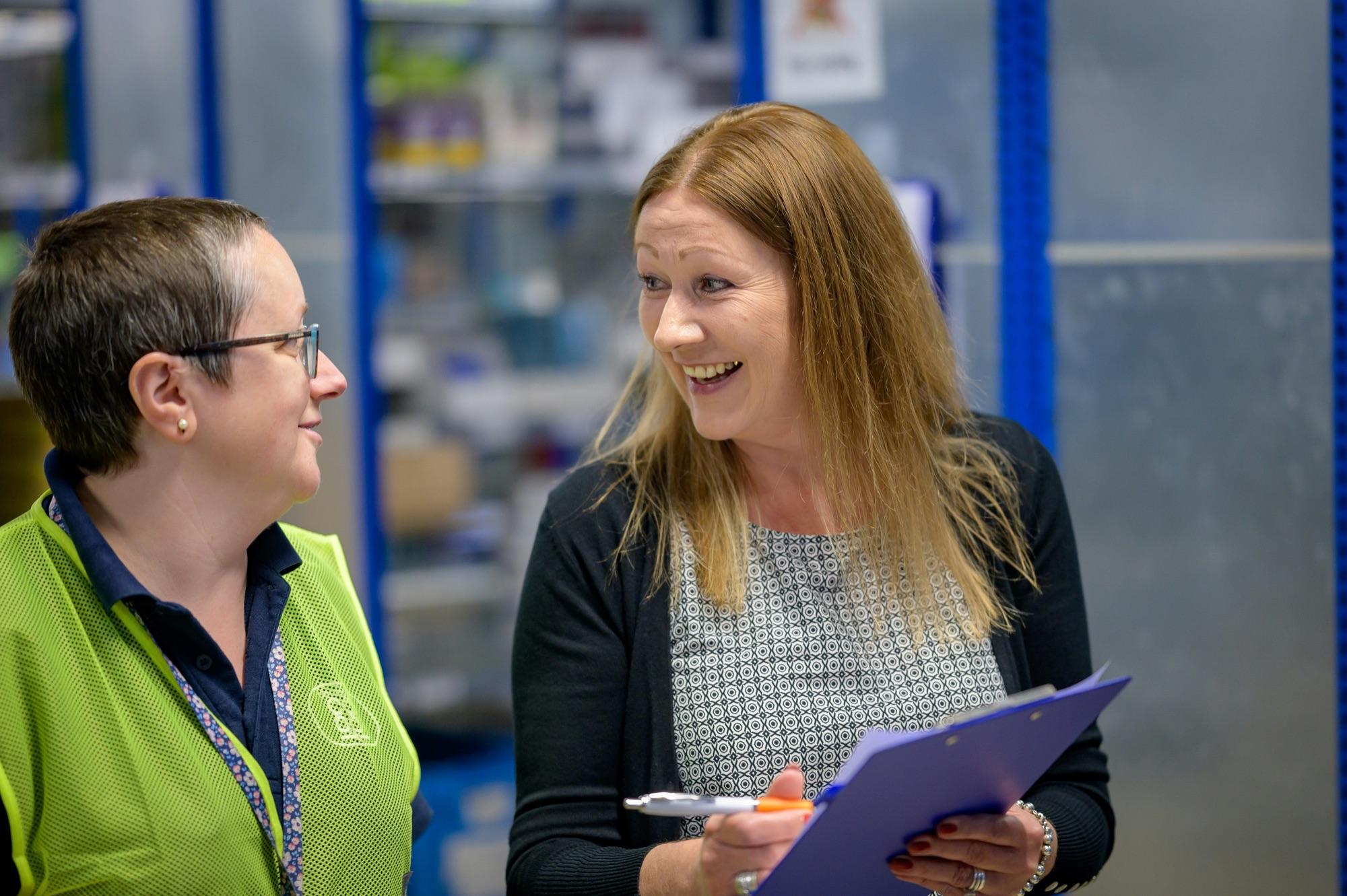 Two colleagues reviewing information together in a warehouse